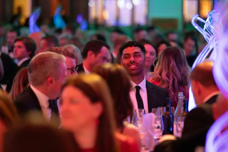 Leon Greenwood smiling at a table during a black-tie evening event