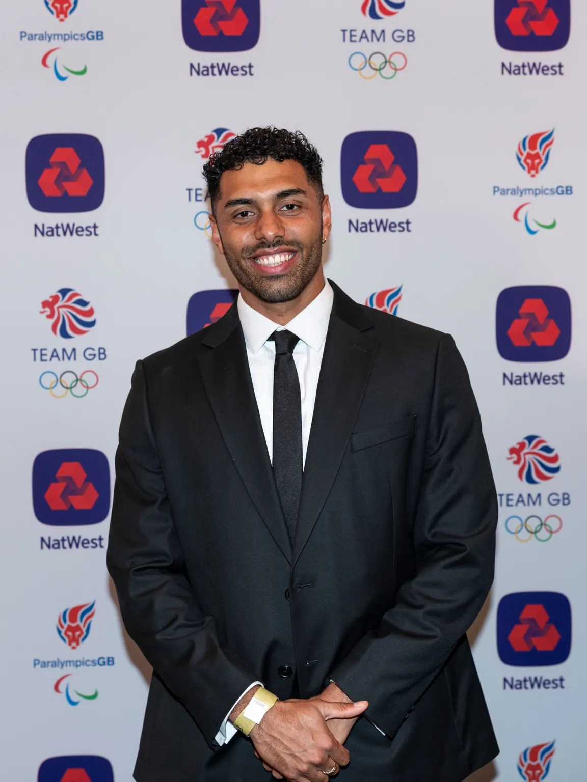 Portrait of Leon Greenwood smiling in a dark suit and tie